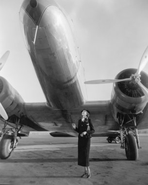Woman standing under a large aircraft looking up clipart