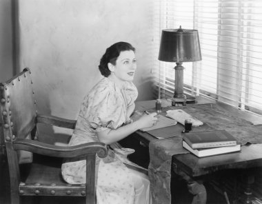 bir mektup yazma masasında oturan genç kadın