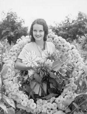 Young woman sitting in garden in a wreath of flowers clipart