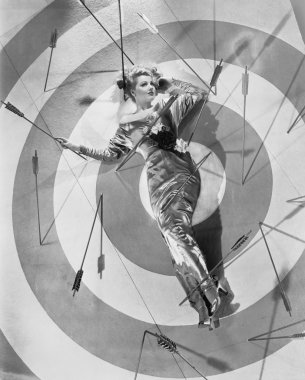 A target of desire, a young woman lying on the bulls eye with arrows around her clipart