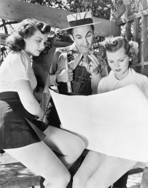 Two young women and a man looking at architectural plans clipart