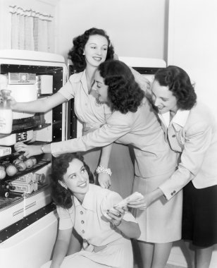 Four women taking things from a refrigerator clipart
