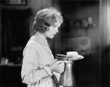 bir fincan kahve ve bir plaka ile ekmek taşıyan genç bir kadın