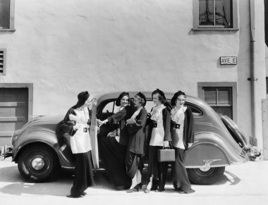 Beş kadın bir arabanın önünde duran