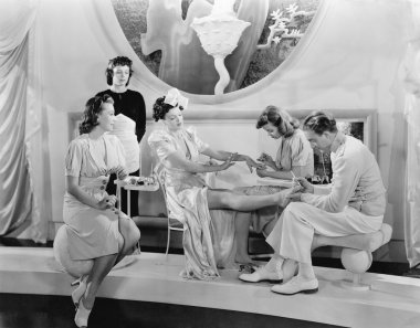 Young woman being pampered by three women and a man clipart