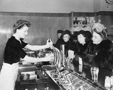 Three woman and a man sitting in a soda fountain clipart