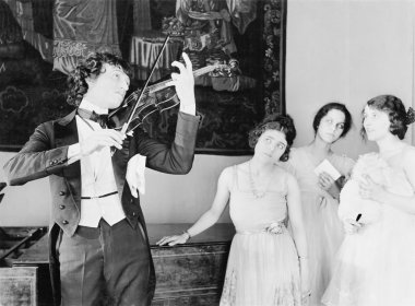 Three young women looking with adoration at a violin player clipart