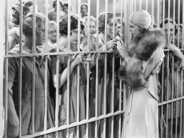 One woman standing in front of a jail talking with a group of women clipart