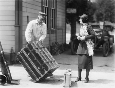 Woman and a porter carrying her trunk clipart