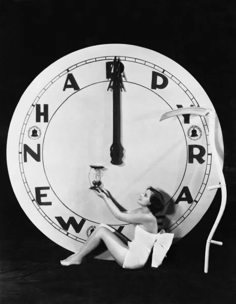 Mujer con reloj a medianoche en Nochevieja — Foto de Stock