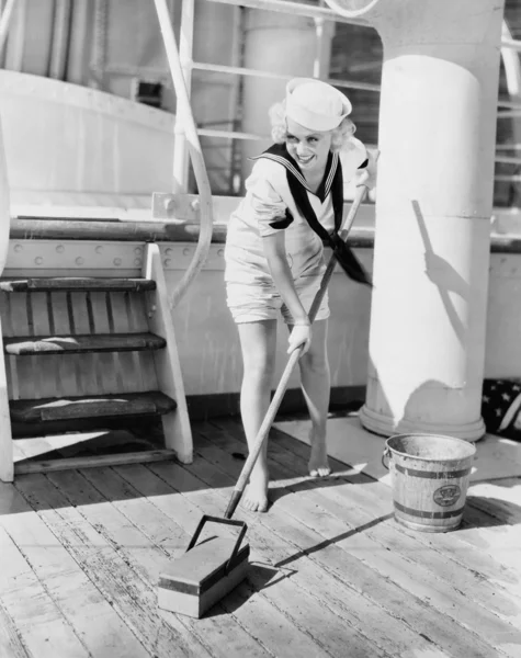 Marinheiro fêmea esfregando baralho de barco — Fotografia de Stock