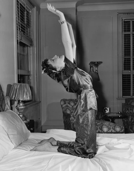 Vrouw die zich uitstrekt op bed — Stockfoto