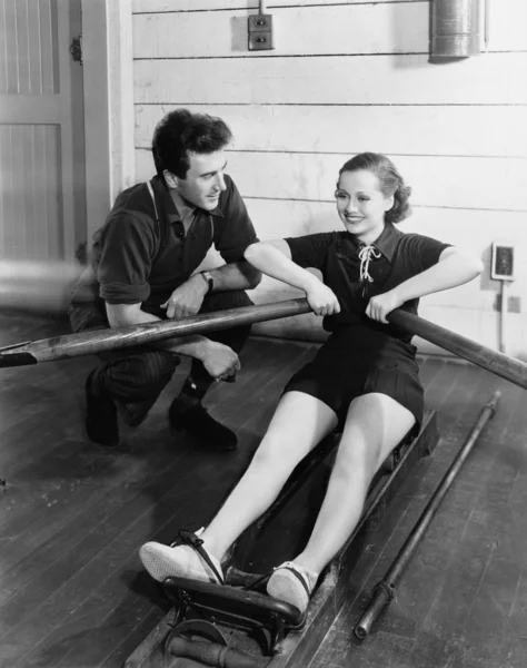 Hombre con mujer usando máquina de remo — Foto de Stock
