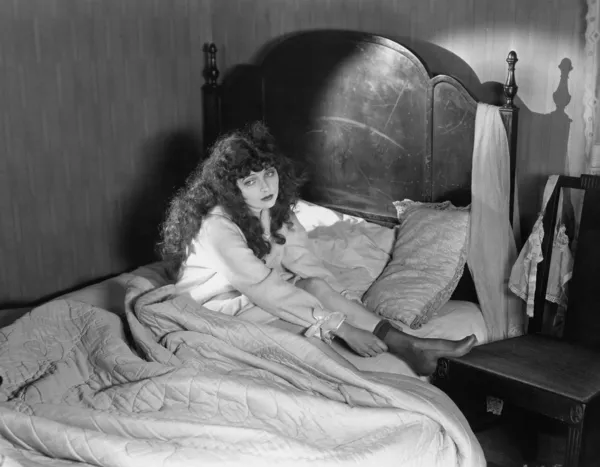 Θλιβερή γυναίκα που κάθεται στο κρεβάτι — Φωτογραφία Αρχείου