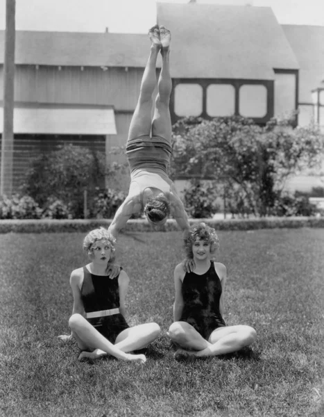 Acrobat balancing on womens shoulders — Stock Photo, Image