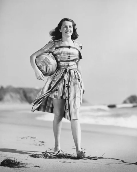 Kvinnan promenader på stranden transporterar bollen — Stockfoto