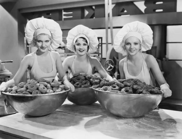 Drie vrouwen met enorme kommen van donuts — Stockfoto