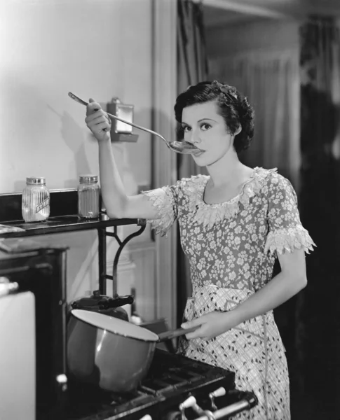 ストーブの上調理食品の試飲の女性 — ストック写真