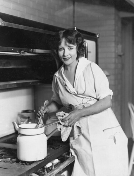 Portrait of woman stirring pot on stove