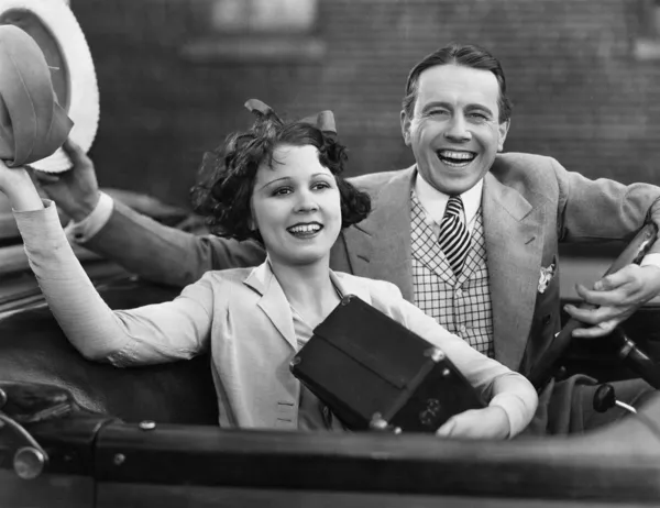 Portrait of happy couple waving in car — Stock Photo, Image