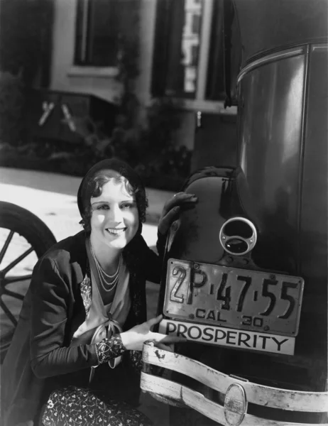 Vrouw met welvaart ondertekenen op auto bumper — Stockfoto