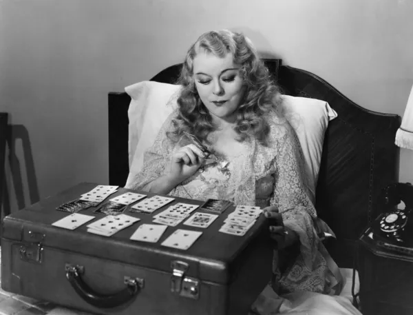Frau spielt Karten im Bett — Stockfoto