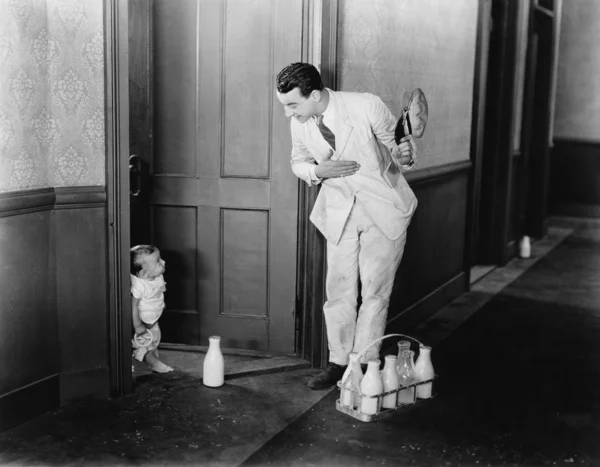Молочник здоровается с ребенком у двери — стоковое фото