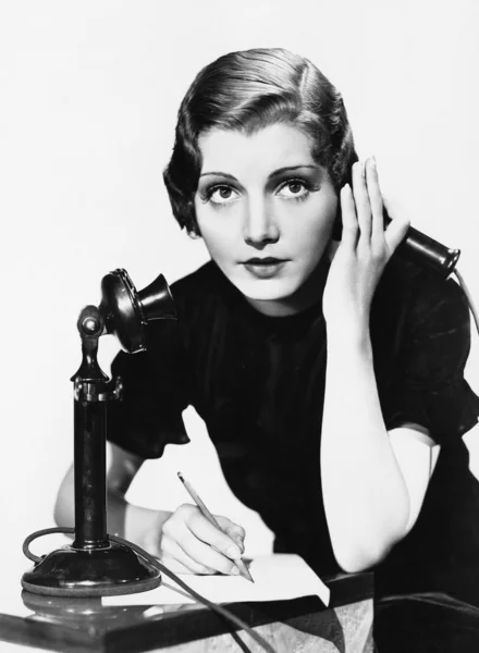Retrato de mulher ao telefone tomando notas — Fotografia de Stock