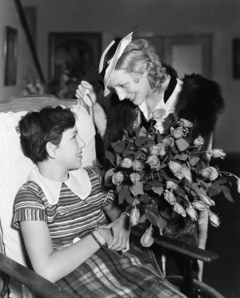 Žena dávat květiny s holkou na vozíku — Stock fotografie