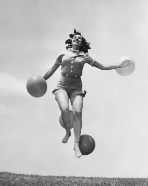 Женщина выпрыгивает наружу с воздушными шарами — стоковое фото
