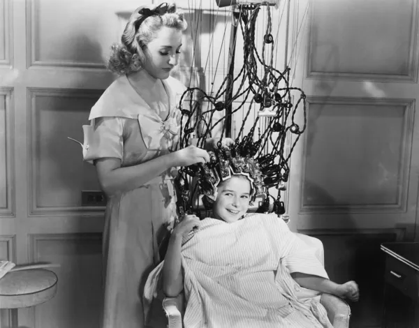 Genç kız saç tarzı için makine kullanan kadın — Stok fotoğraf