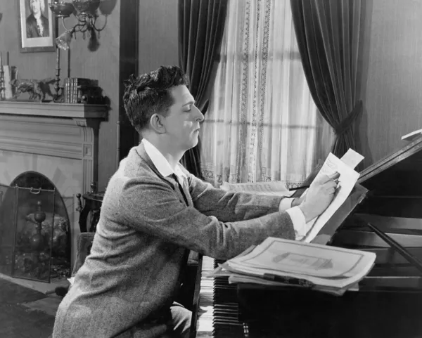 Homme au piano écrivant sur une partition — Photo