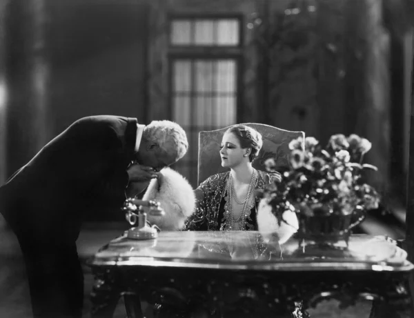 Мужчина целует руку женщины сидящей за столом — стоковое фото