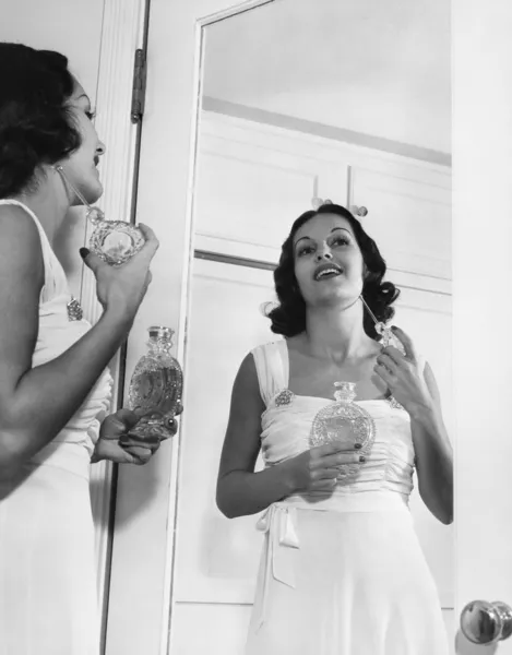 Woman applying perfume at mirror — Stock Photo, Image