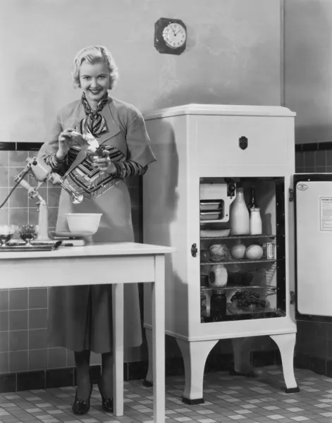 Женщина с холодильником и смесителем на кухне — стоковое фото