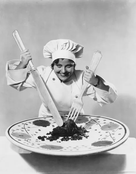 Μάγειρας με το φαγητό στο πιάτο υπερμεγέθη με υπερμεγέθη σκεύη — Φωτογραφία Αρχείου