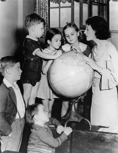 Mulher e crianças olhando para o globo — Fotografia de Stock
