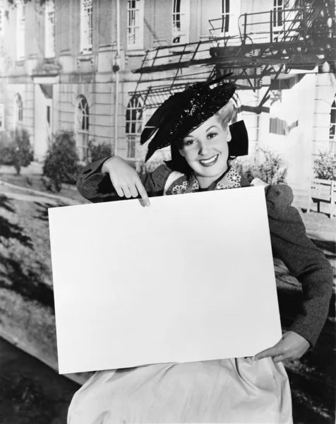 Mujer sonriente sosteniendo un cartel en blanco — Foto de Stock