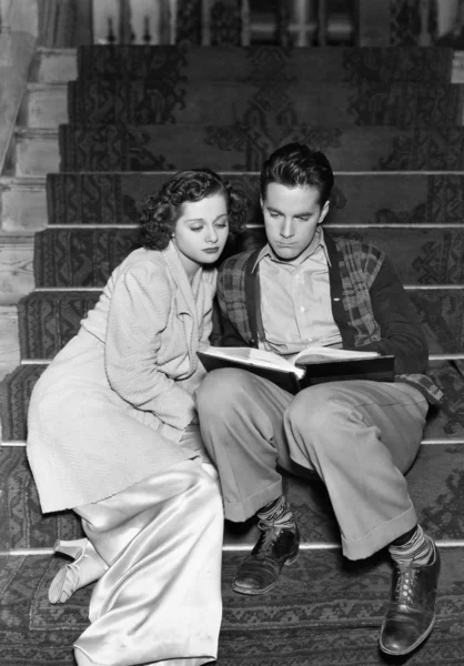 Casal lendo juntos nas escadas — Fotografia de Stock
