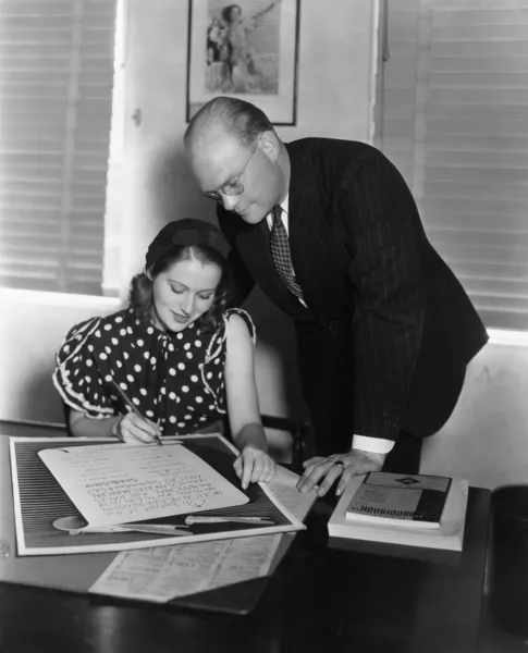 Homme supervisant femme signant le document — Photo