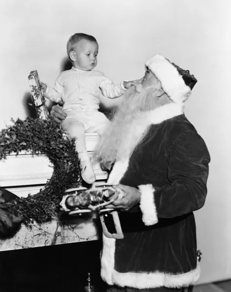Santa Claus con bebé en el manto — Foto de Stock