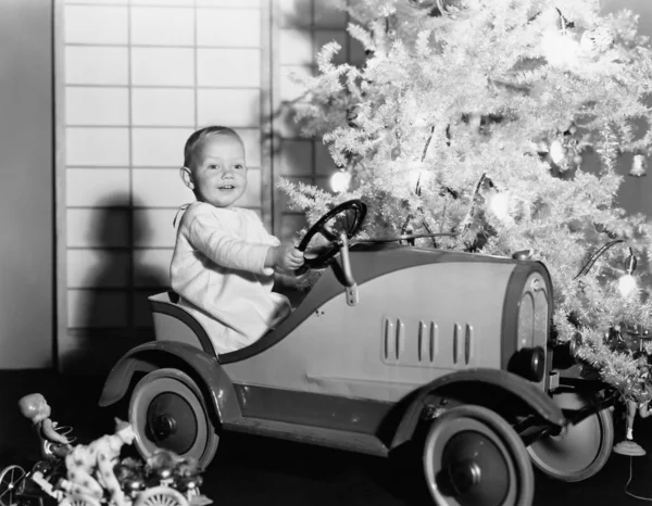 Ребенок с игрушечной машиной под елкой — стоковое фото