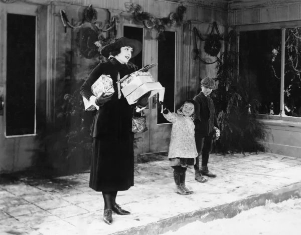 Женщина и дети на улице с рождественскими подарками — стоковое фото