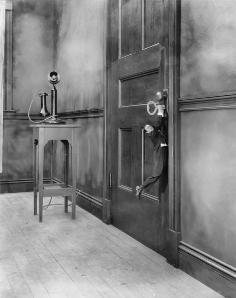 Mały człowiek wisi klucz w drzwiach — Zdjęcie stockowe