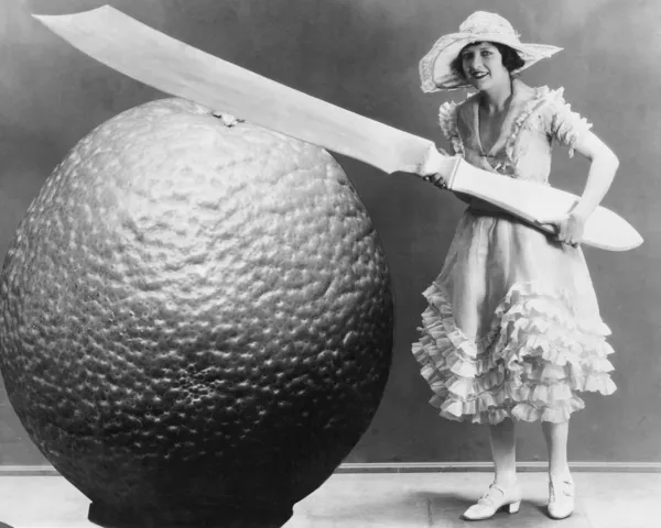 Žena s velkým nožem a kousek ovoce — Stock fotografie