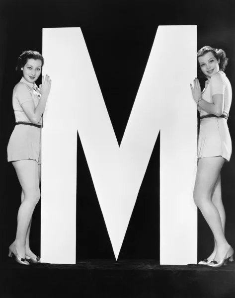 Zwei Frauen posieren mit riesigen Buchstaben m — Stockfoto