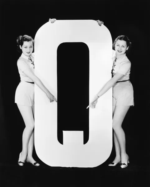 Duas mulheres apontando para a carta enorme Q — Fotografia de Stock