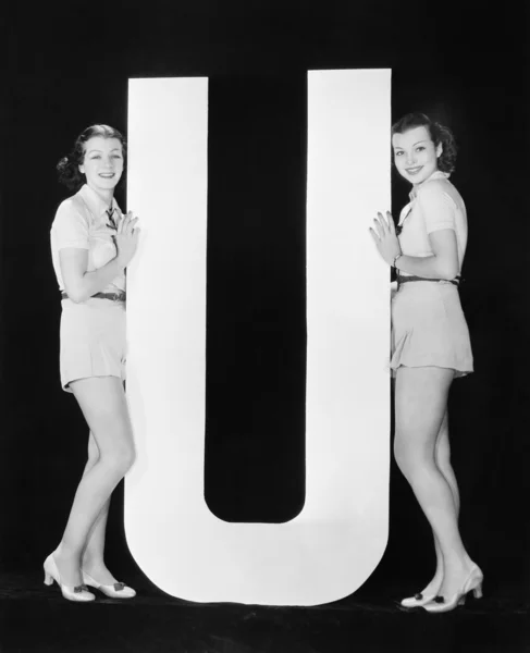 Женщины позируют с огромной буквой U — стоковое фото