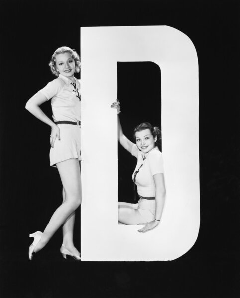 Women posing with huge letter D