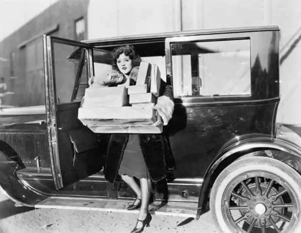 Woman carrying packages from car — Stockfoto